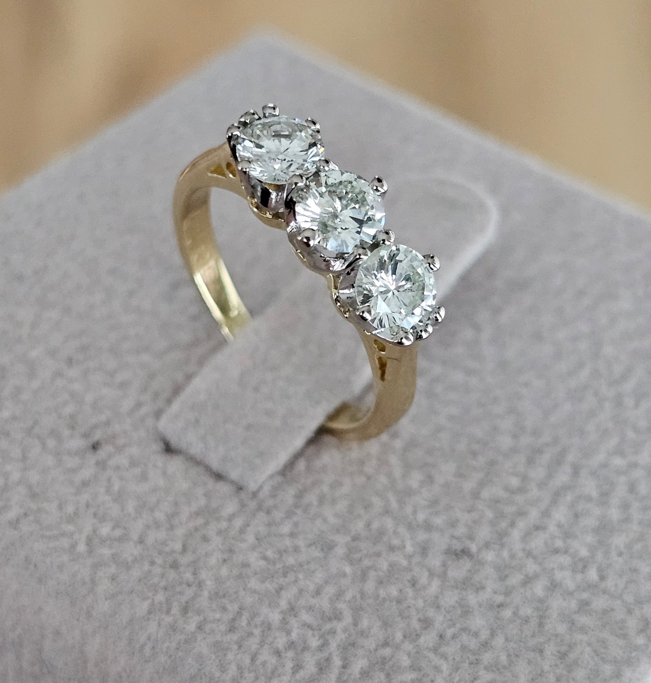 Gold ring with three diamonds on a gray surface