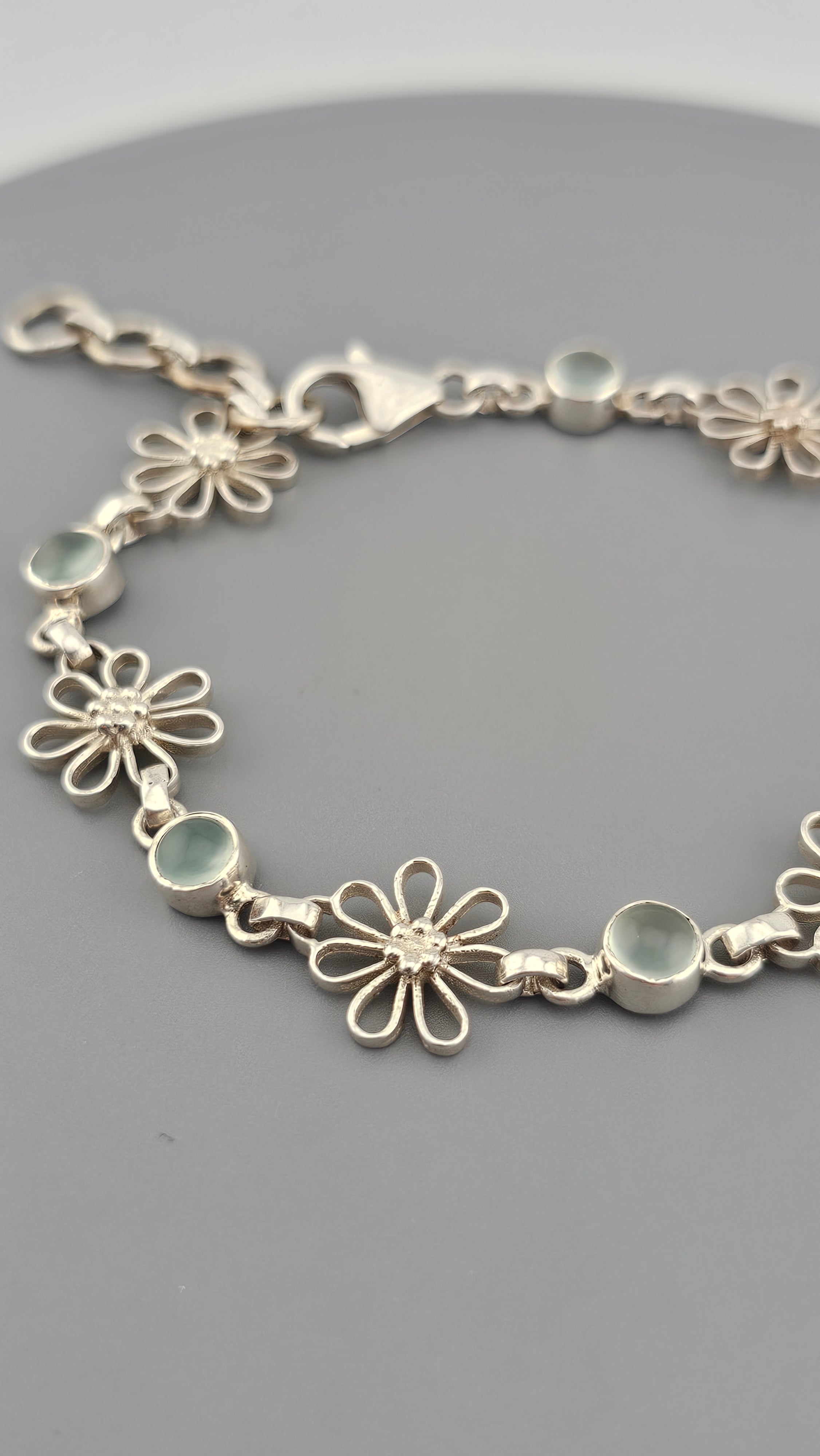 925 sterling silver daisy link bracelet featuring light blue, round cabochon aquamarine