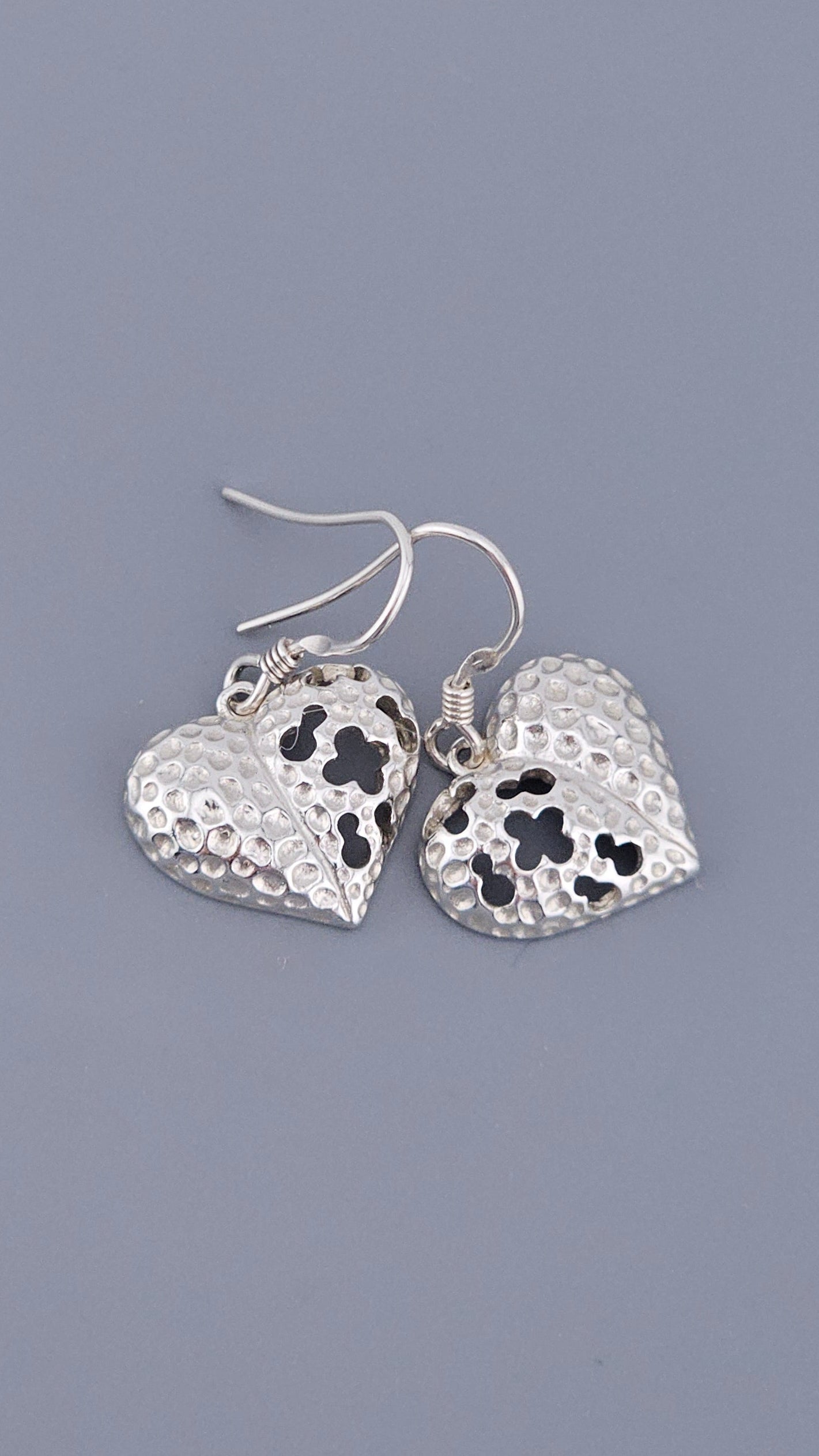 Silver heart-shaped earrings on a gray background