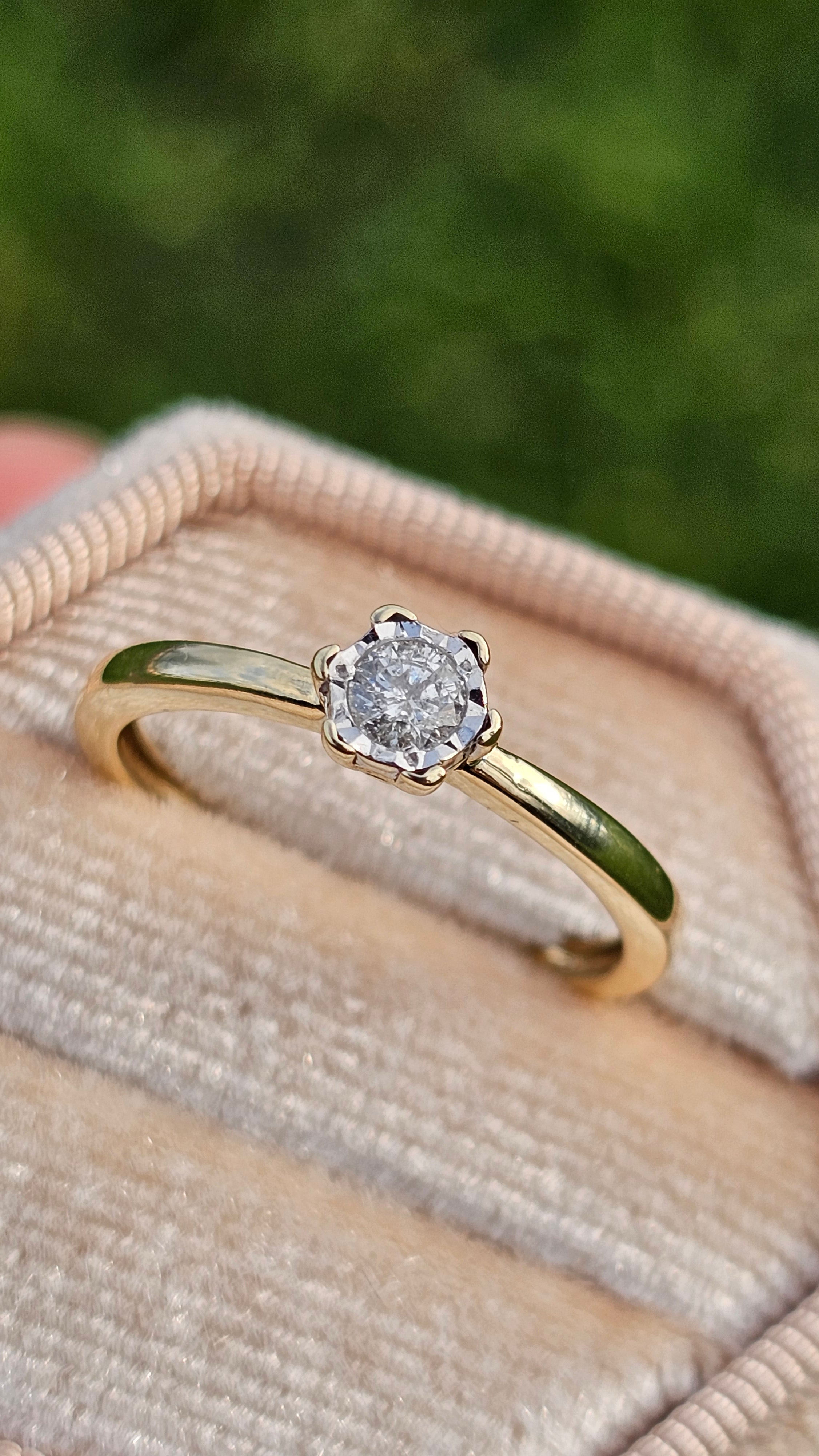 Gold ring with a diamond on a beige fabric background