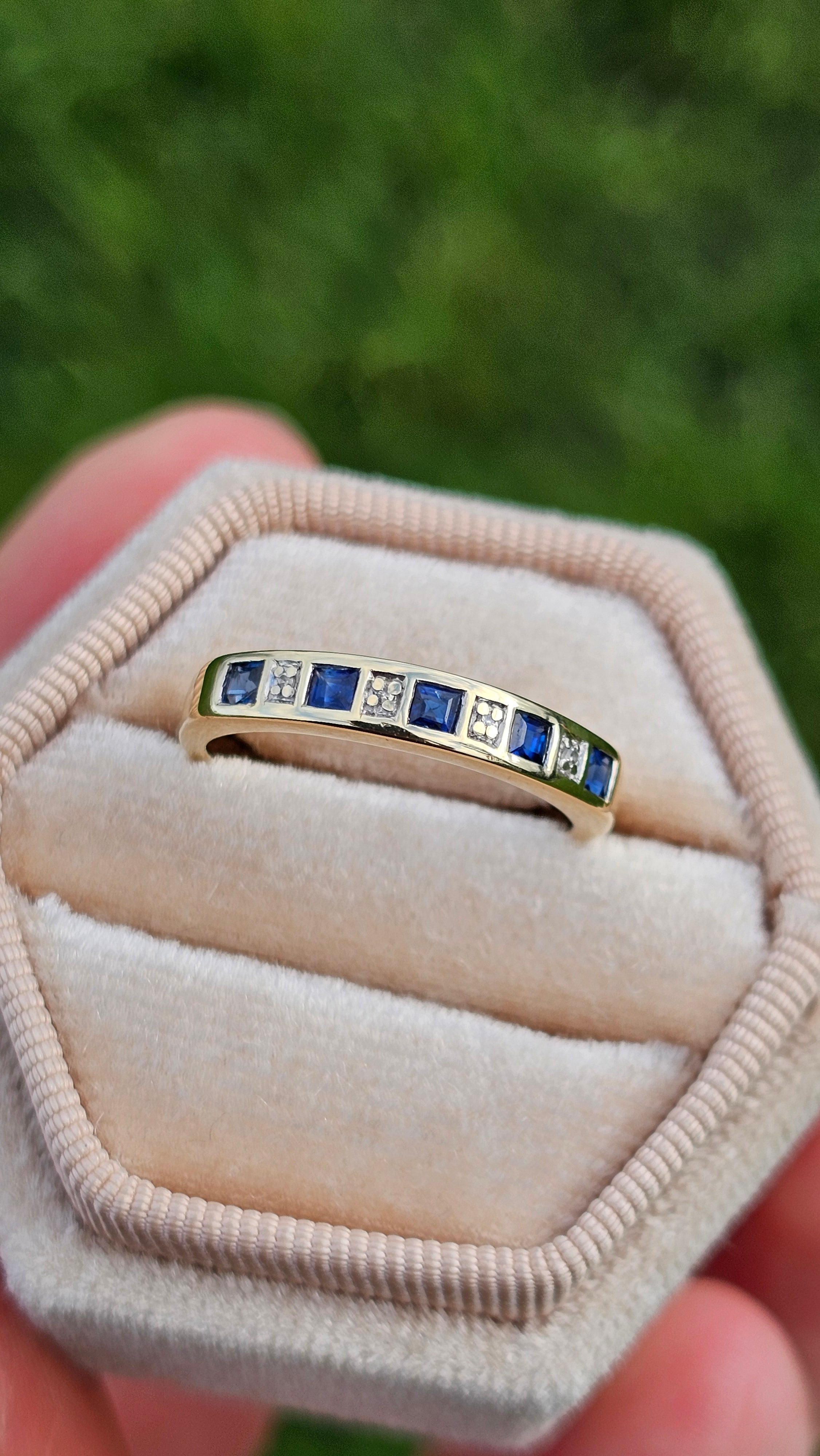 Gold ring with blue gemstones on a beige cushion