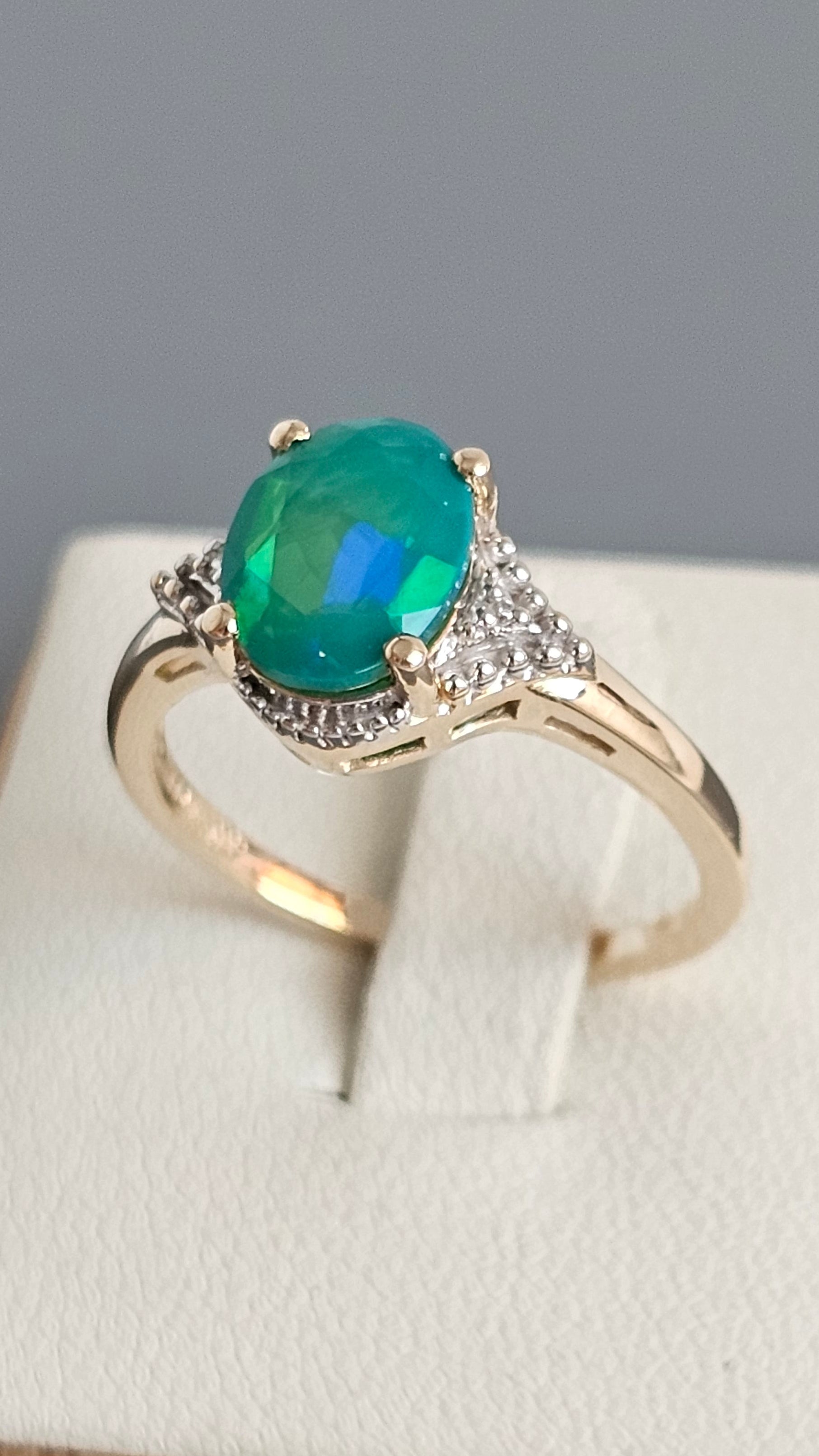 Gold ring with a green gemstone on a white box