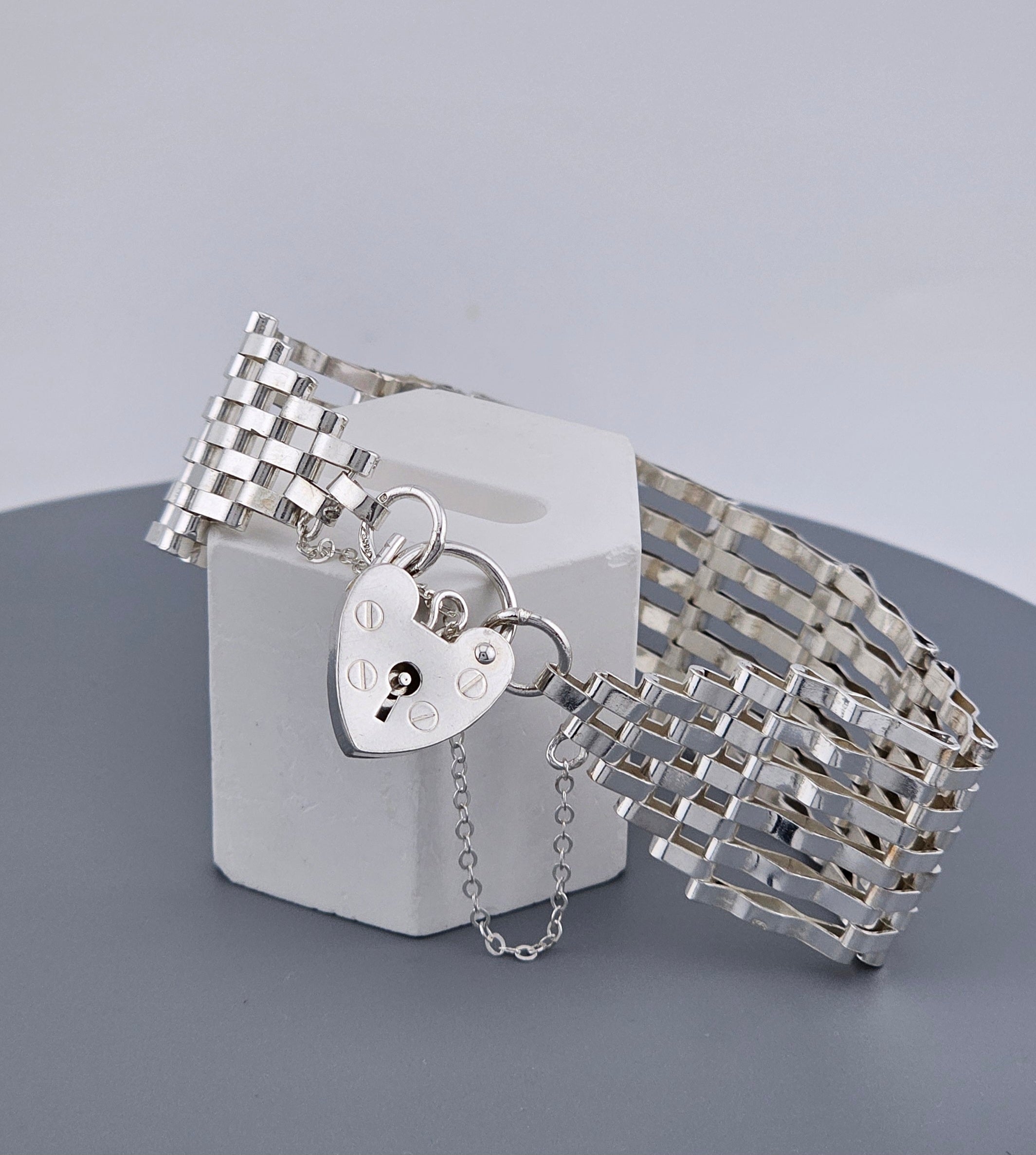 Silver bracelet with a heart-shaped padlock charm on a gray background