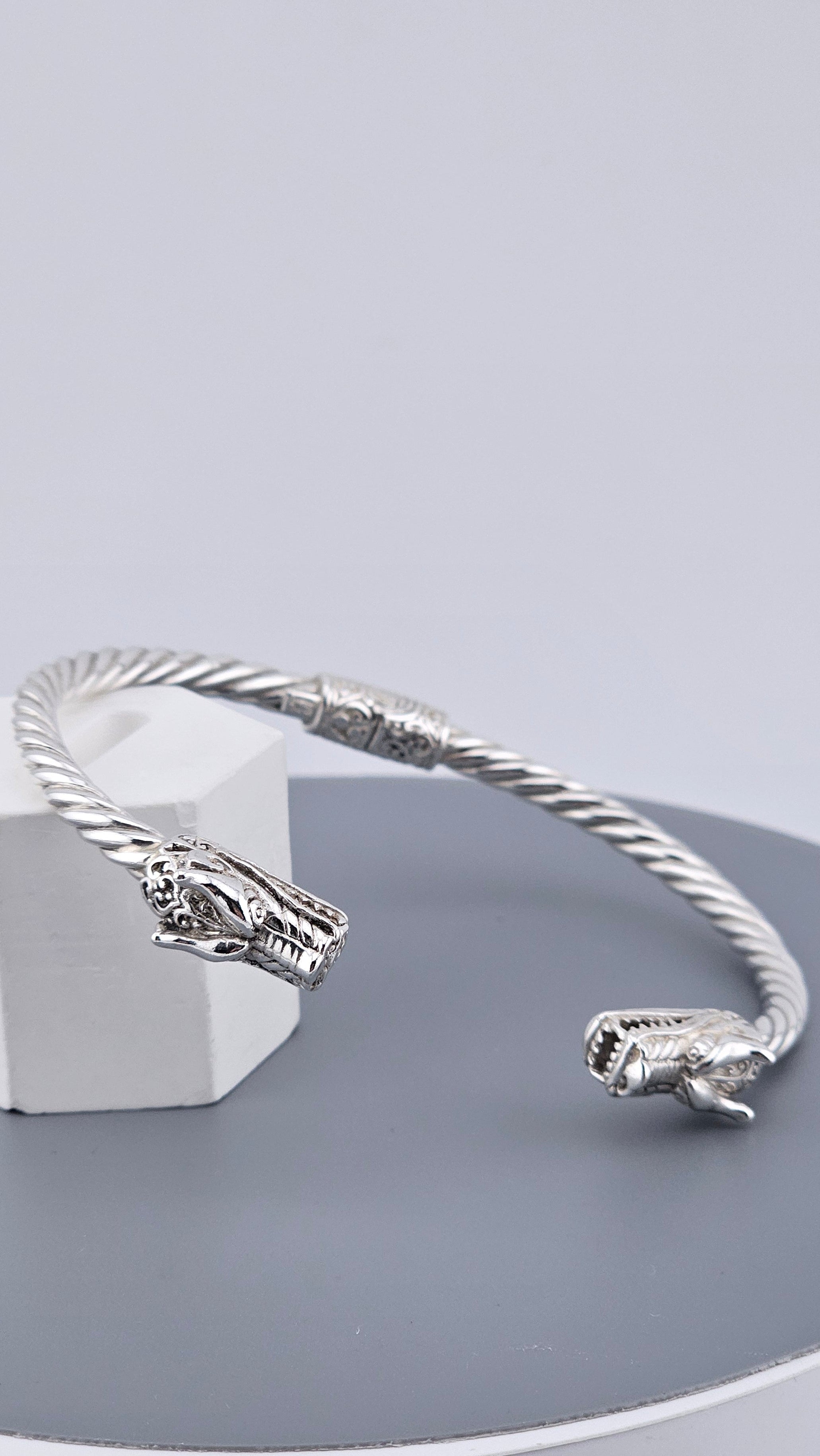 Silver bracelet on a gray stand with a light gray background