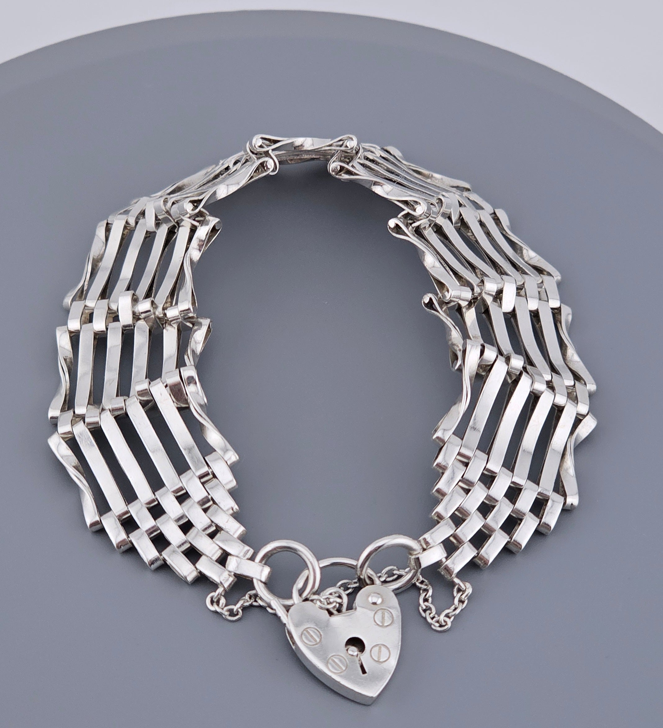 Silver bracelet with a heart-shaped padlock charm on a gray background